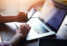 6 Tips for Recognizing Illegal Streaming Websites adult hands holding mobile phone over laptop keyboard