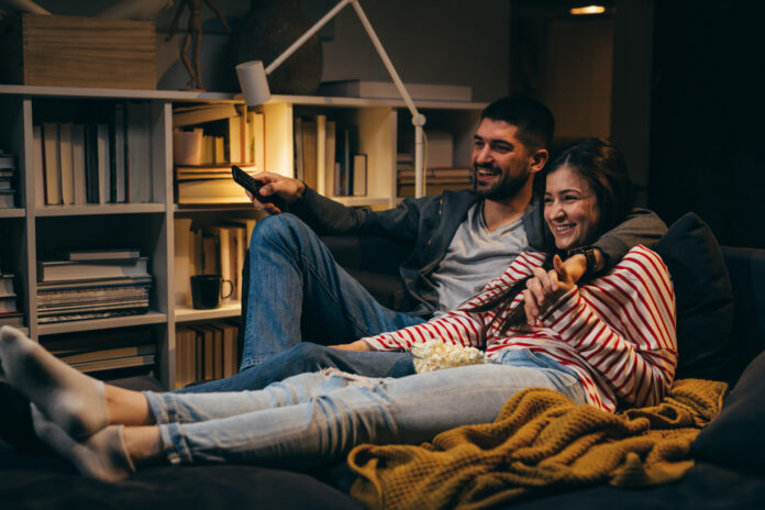 young couple enjoying time at home. evening night scene Young couple sitting together on the couch in the dark while watching a movie at home.